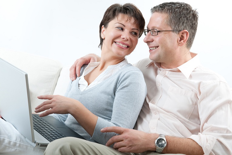 "couple smiling at each other while woman holds laptop"
