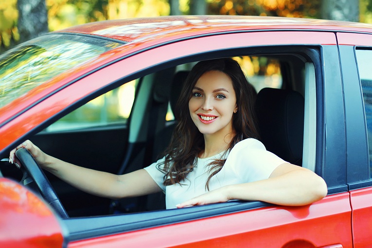 young women with brown hair white t-shirt driving red car in fall