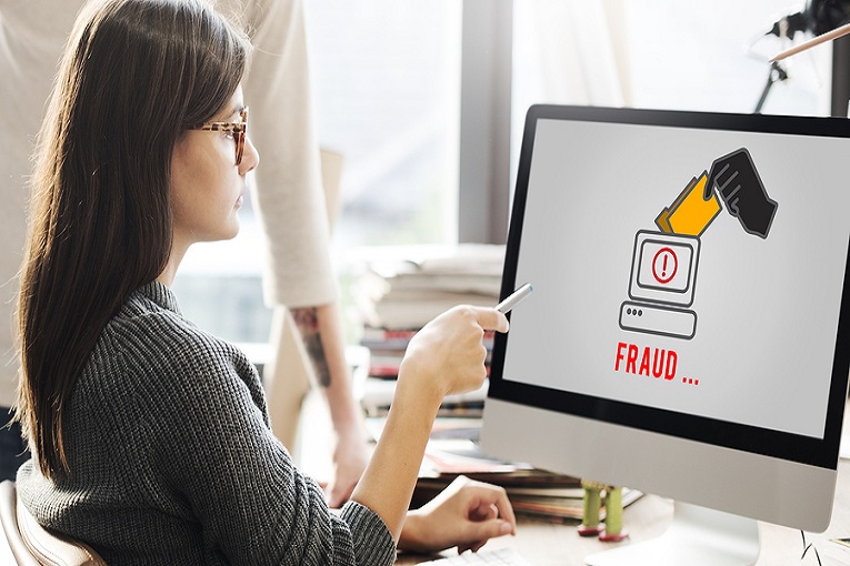 "woman looking at computer screen that says Fraud"