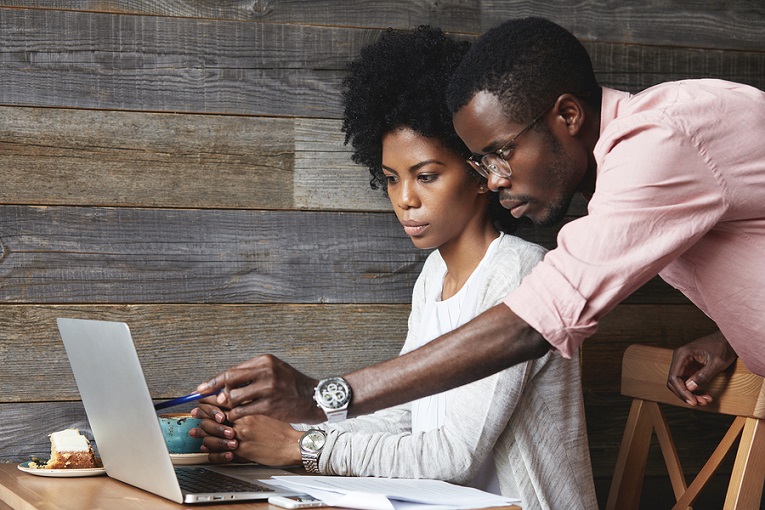 "man helping woman at laptop"