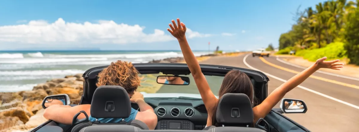 people in convertible car driving