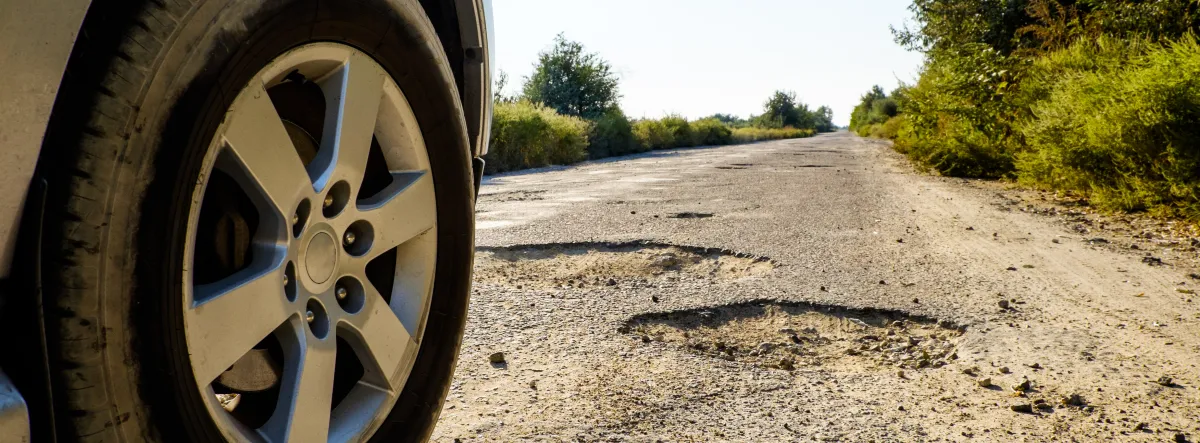 car driving on road with potholes