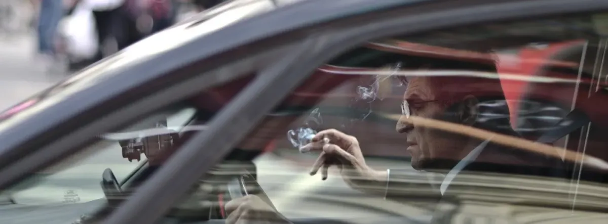 man with a cigarette driving a car 
