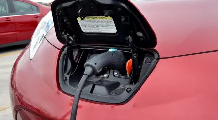red electric car with charger plugged in
