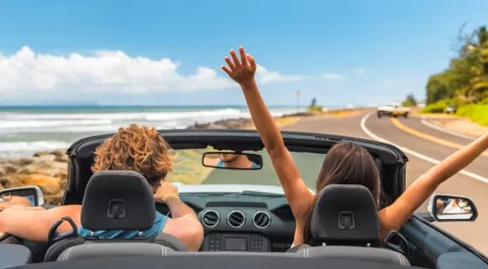 people in convertible car driving