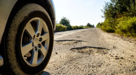 car driving on road with potholes