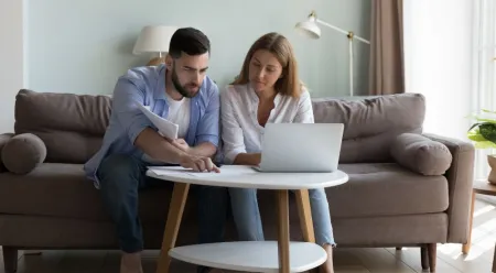 couple on couch looking at paperwork