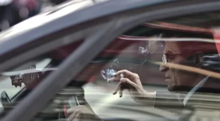 man with a cigarette driving a car 